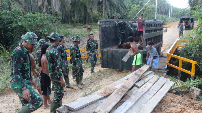 Warga Bantu Satgas TMMD Kodim Sanggau Turunkan Papan untuk Rehab Jembatan
